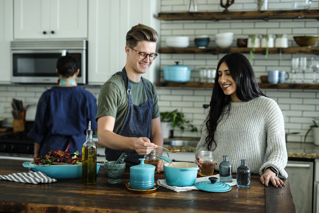 smiling-man-standing-and-mixing-near-woman-in-kitchen-area-of-the-house-bg5rhvrh0jm